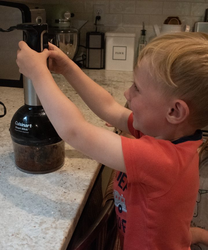 young child hand blending dates to make no bake energy bites