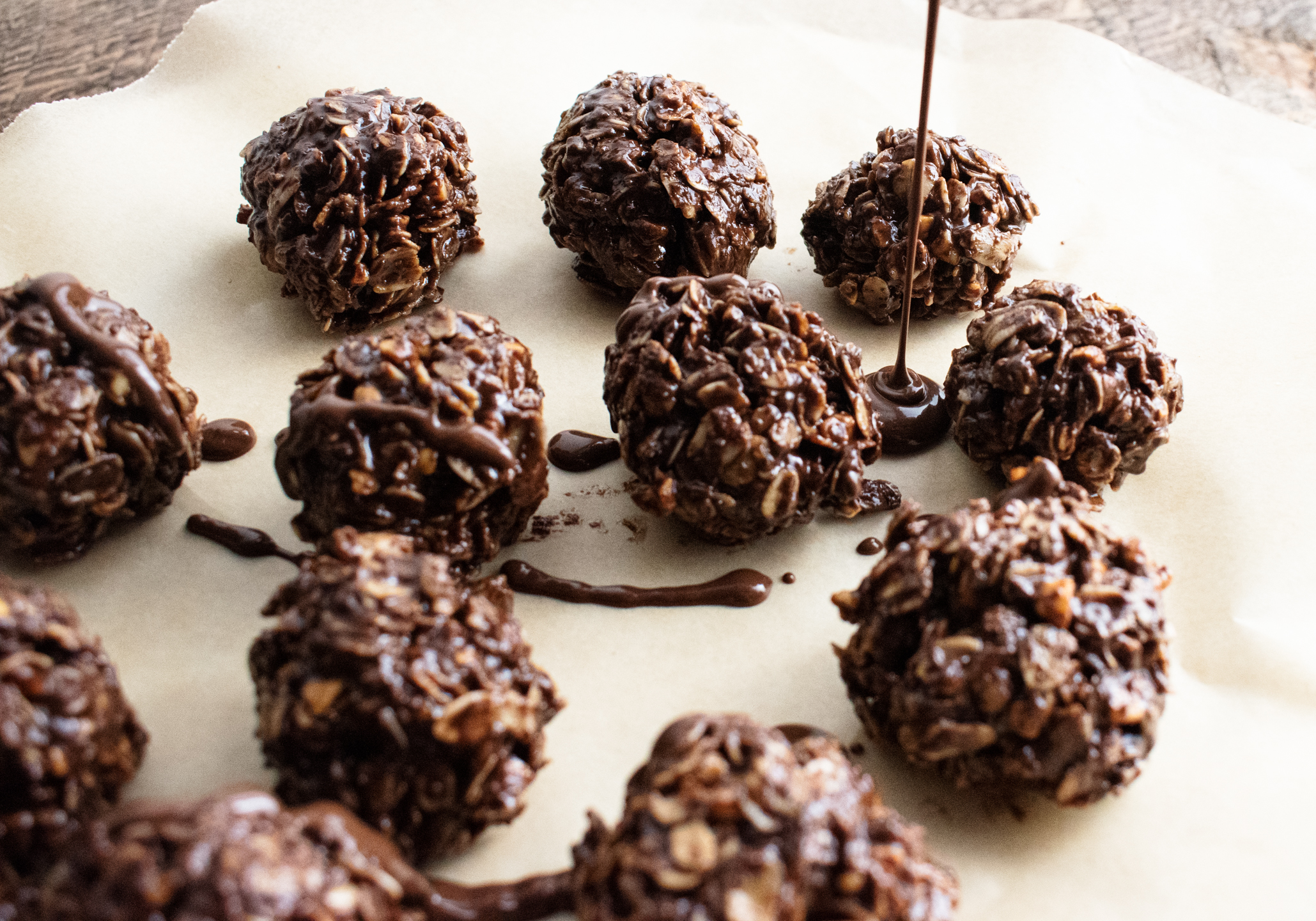 close up of chocolate peanut butter balls on a white plate with chocolate drizzling