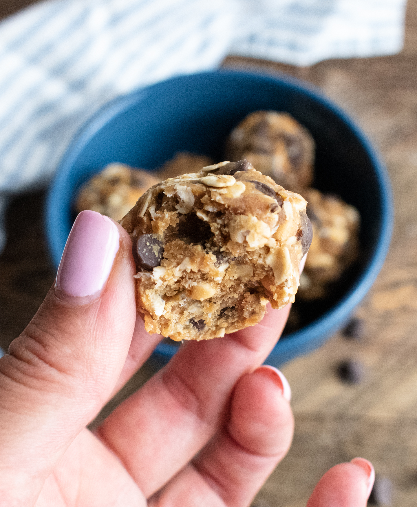 a hand holding a no bake energy ball that has a bite taken out of it