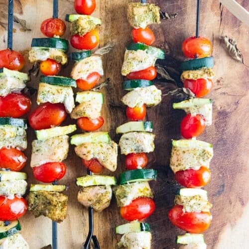 Grilled Chicken Pesto Kabobs on skewers with a glass of pesto on the side.