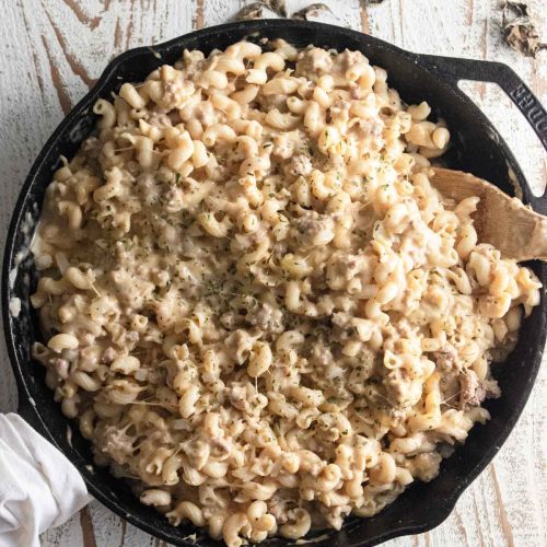 birds-eye view of ground turkey mac and cheese in a Lodge cast-iron skillet on a white wooden table