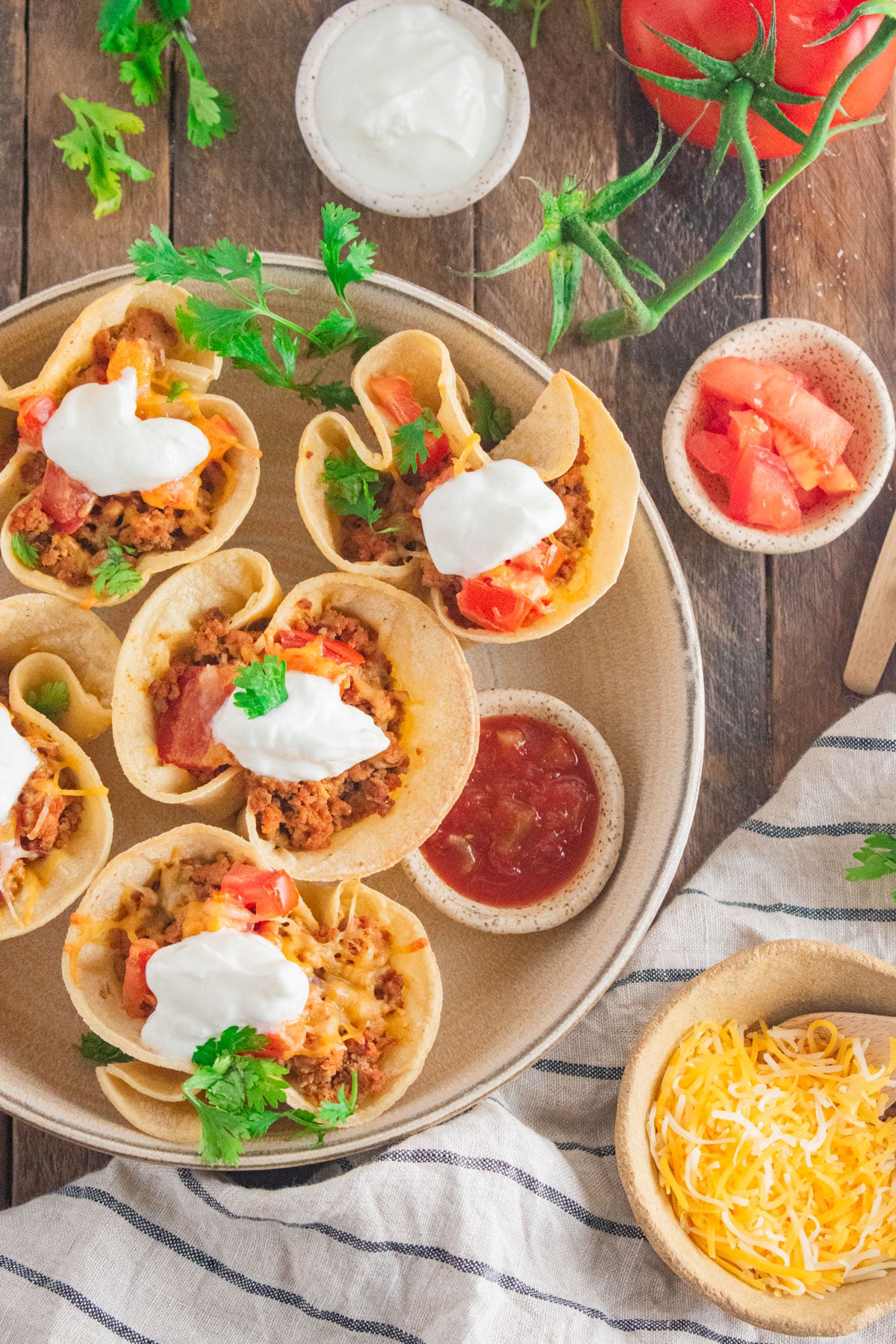 Birds eye view of ground turkey taco cupcakes on a cream colored dish with cilantro scattered around.