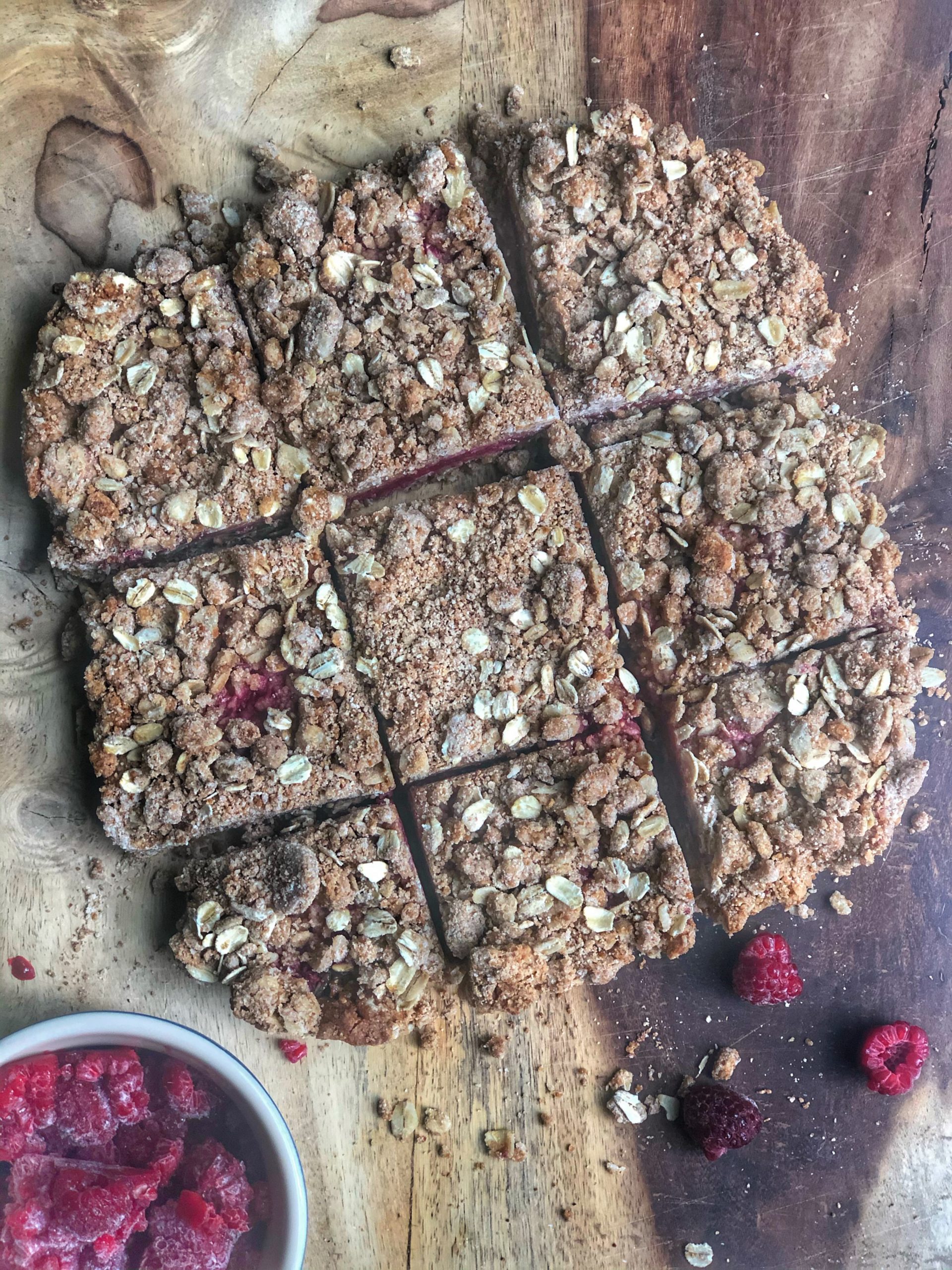 Berry Oatmeal Breakfast Bars on a wooden board with a small bowl of raspberries
