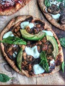 bbq chicken sausage and avocado naan pizza on a wooden board