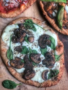 spinach mushroom and cheese naan pizza on a wooden board