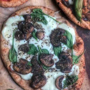 spinach mushroom and cheese naan pizza on a wooden board