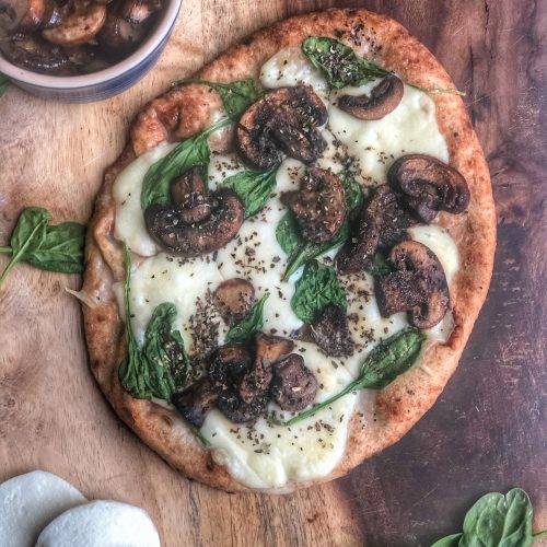 spinach mushroom and cheese naan pizza on a wooden board