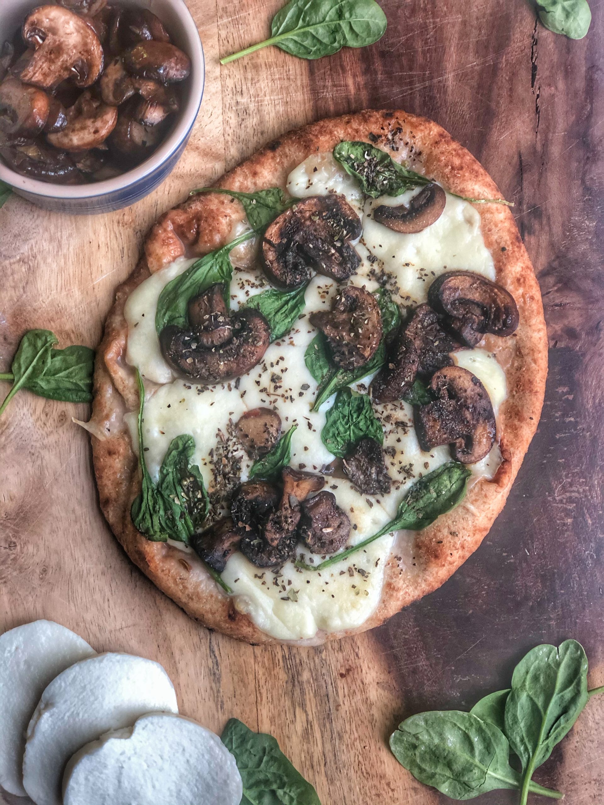 spinach mushroom and cheese naan pizza on a wooden board