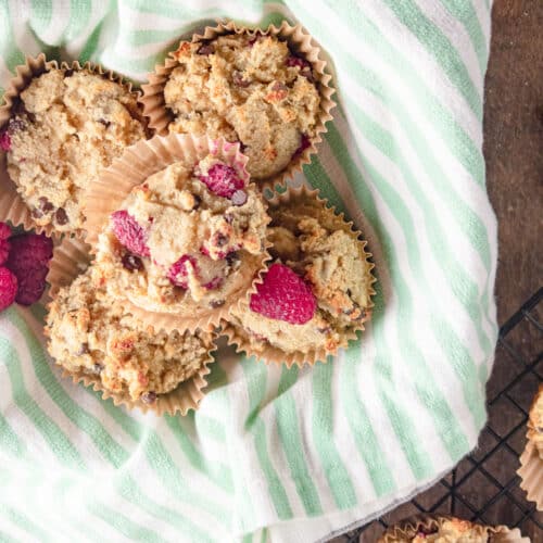 Raspberry muffins in a basket with a green and white striped nakin under the muffins.