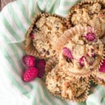 A close up of raspberry banana muffins in a basket with a striped green and white towel.