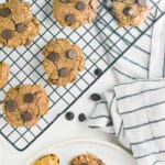 Peanut Butter chocolate chip cookies on a cooling rack and on a white plate with a stripped napking laid on the table.