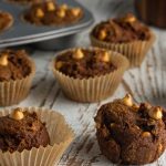 A close-up of the pumpkin butterscotch muffins sitting on a white wooden table.