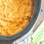 A birds eye view of crockpot buffalo chicken dip with a side of celery and chips.