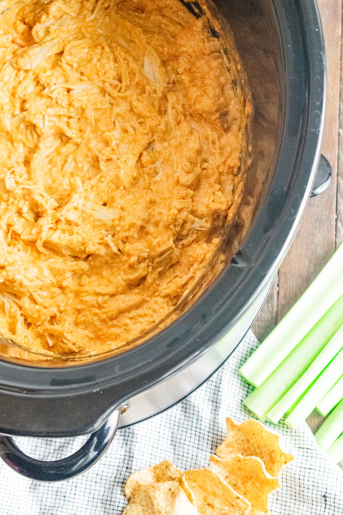 A birds eye view of crockpot buffalo chicken dip with a side of celery and chips.