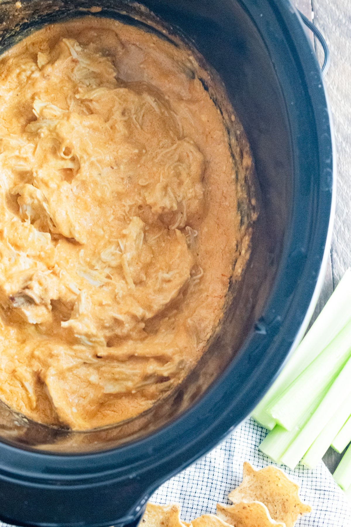 Crockpot buffalo chicken dip with a side of sliced celery and chips.