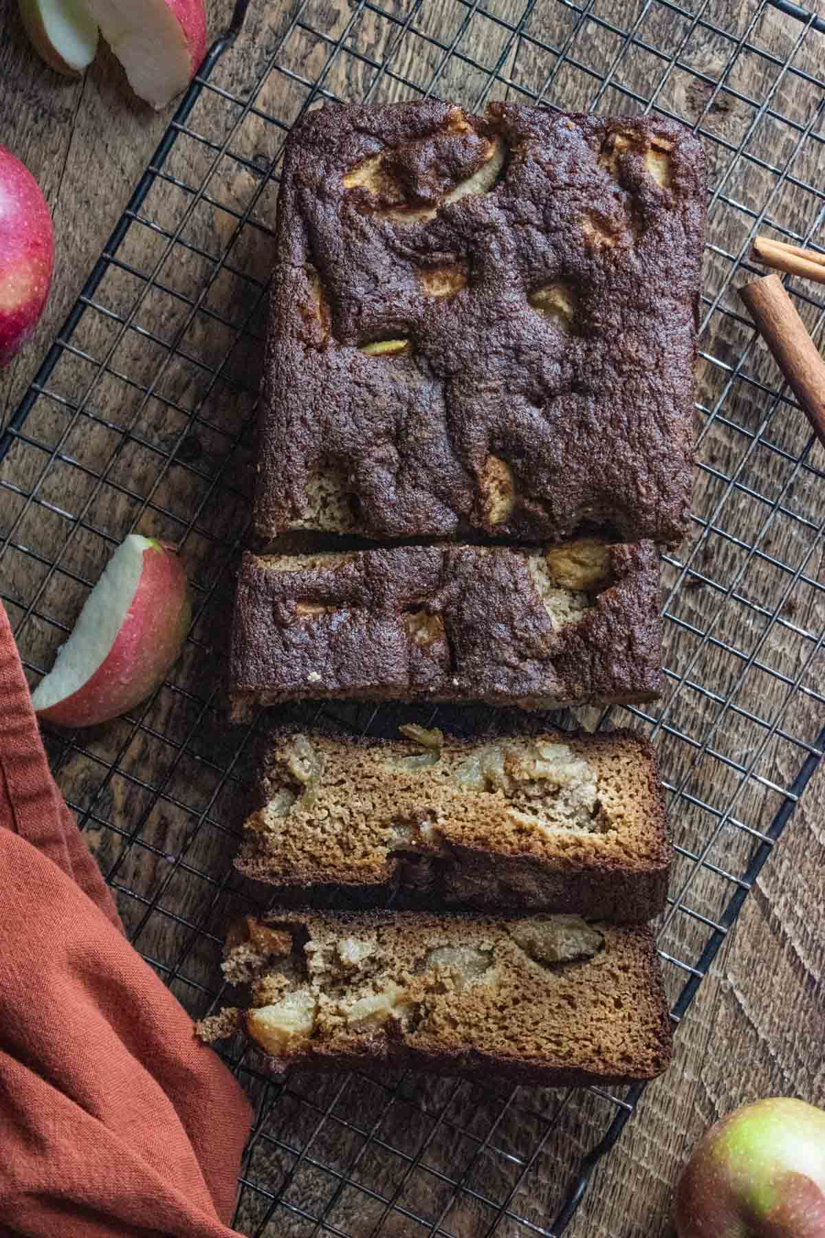 healthy apple bread on a cooling rack with scattered pieces of apples and a red napkin