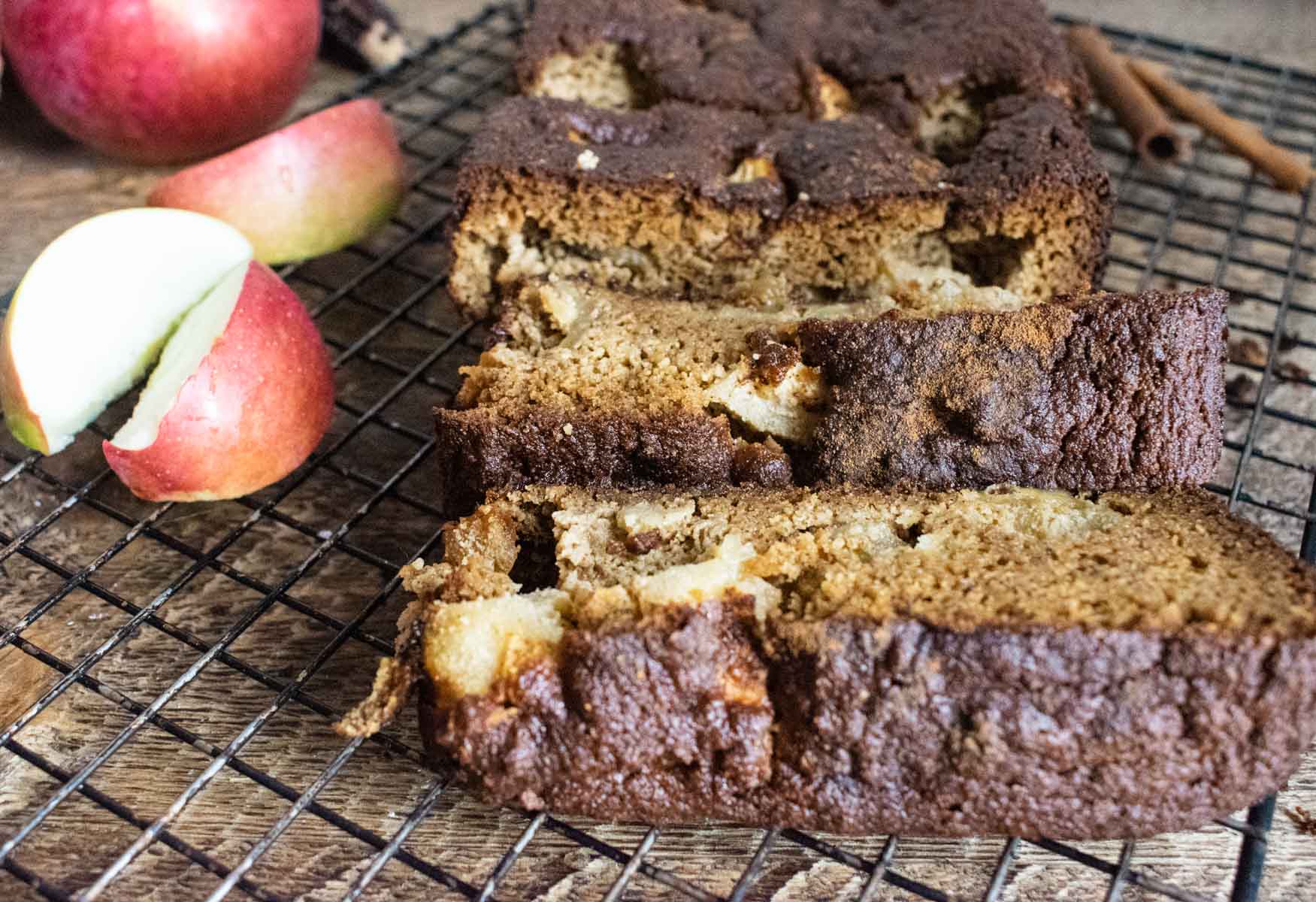 delicious healthy apple bread on a cooling rack with apples pieces next to the bread