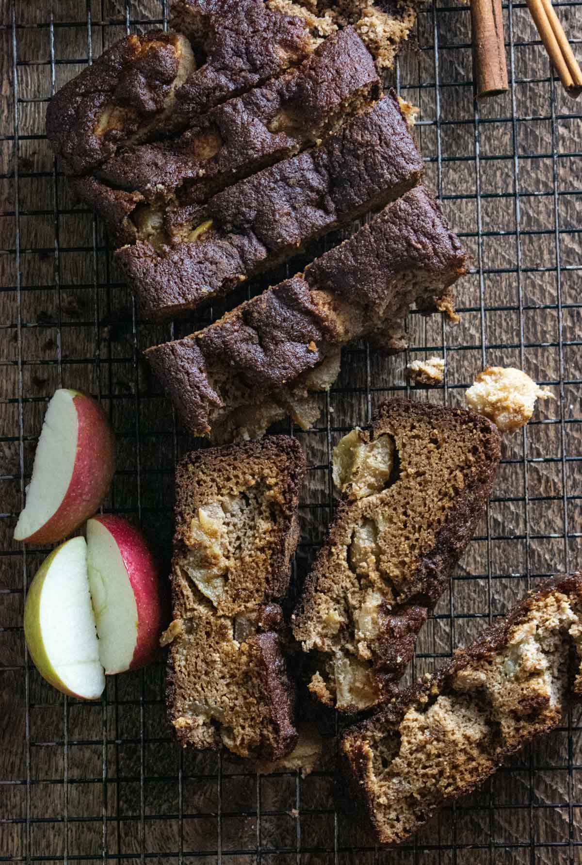 healthy apple bread on a cooling rack cut into slices with scattered apple slices