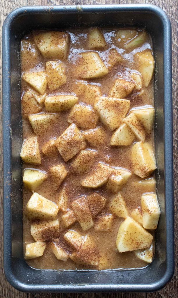 ingredients for healthy apple bread in a loaf pan with cinnamon sprinkled on top