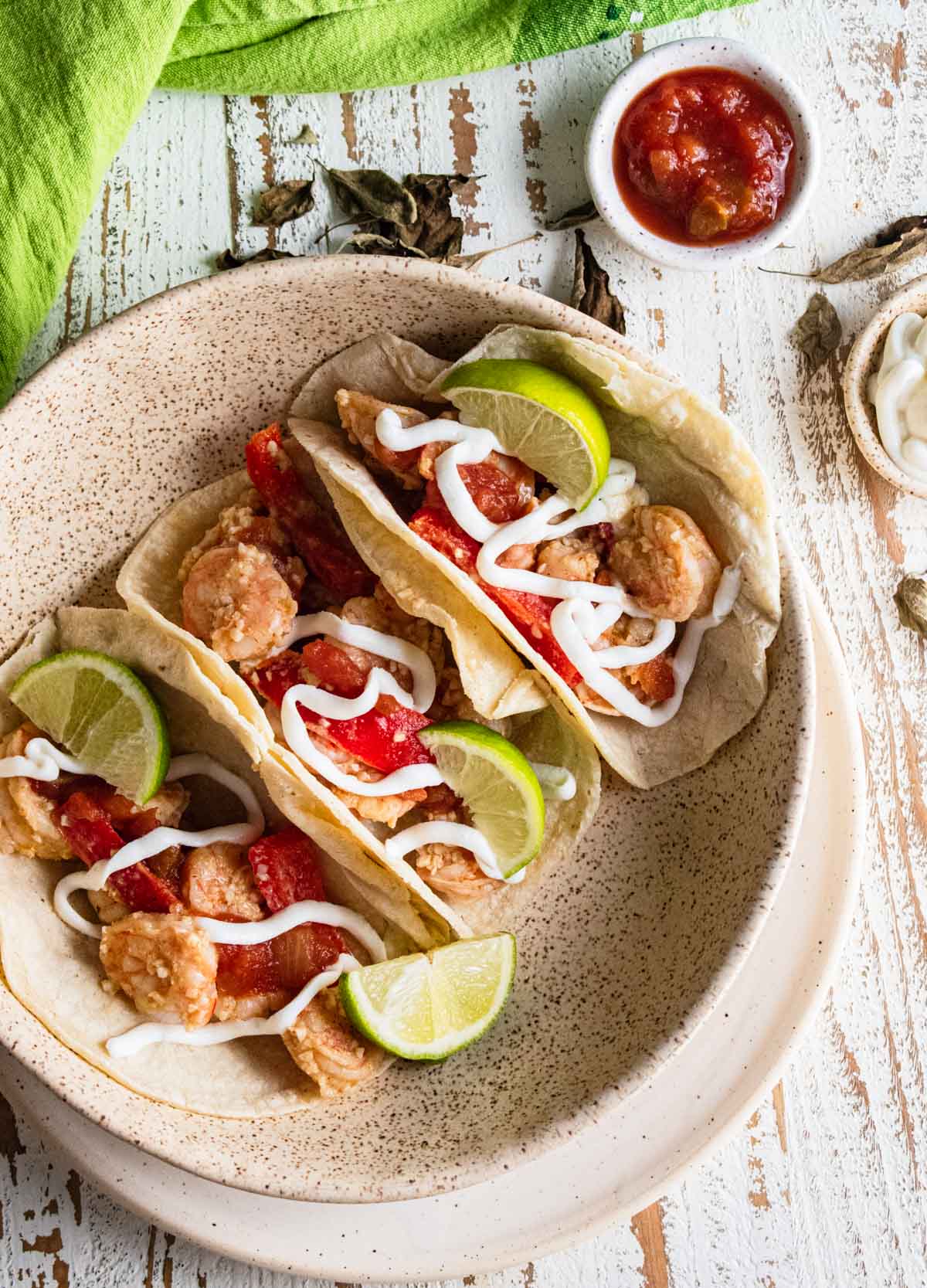 birds-eye view of shrimp tacos topped with lime slices and plain greek yogurt drizzled on top