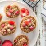 Peanut butter and jelly oatmeal breakfast cups on a white plate and on a cooling rack.