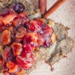 A close up of crispy baked latkes and a cranberry chutney sauce on a cream colored plate.