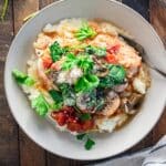 Birds eye view of chicken cacciatore in a white bowl with a stripped napkin laid next to it.