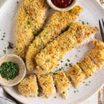 Crispy panko chicken on a white plate sliced into pieces with a little dish of ketchup on the plate.