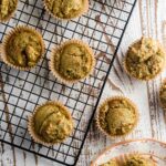 A birds-eye view of matcha muffins on a cooling rack on a white wooden table.
