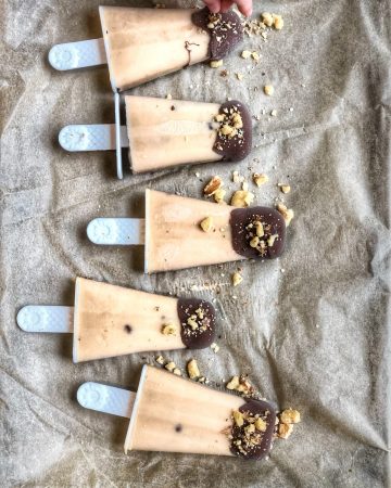 chocolate covered banana peanut butter ice pops lined on parchment paper