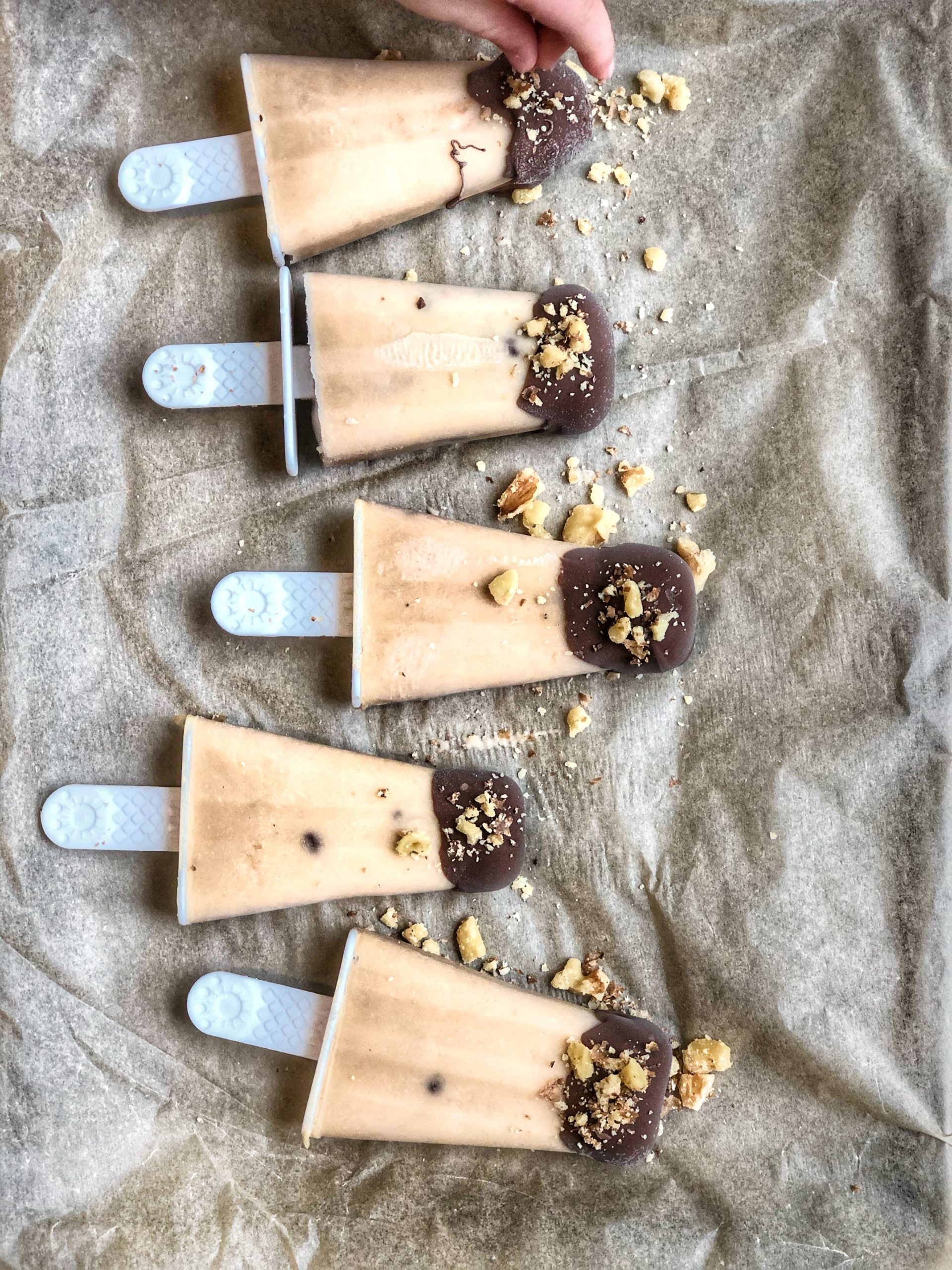 chocolate covered banana peanut butter ice pops lined on parchment paper