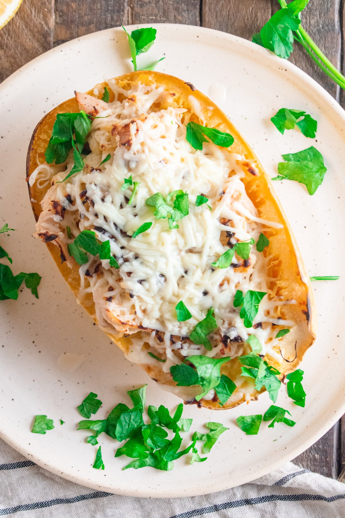Chicken Alfredo in a spaghetti squash on a white plate on a wooden table.