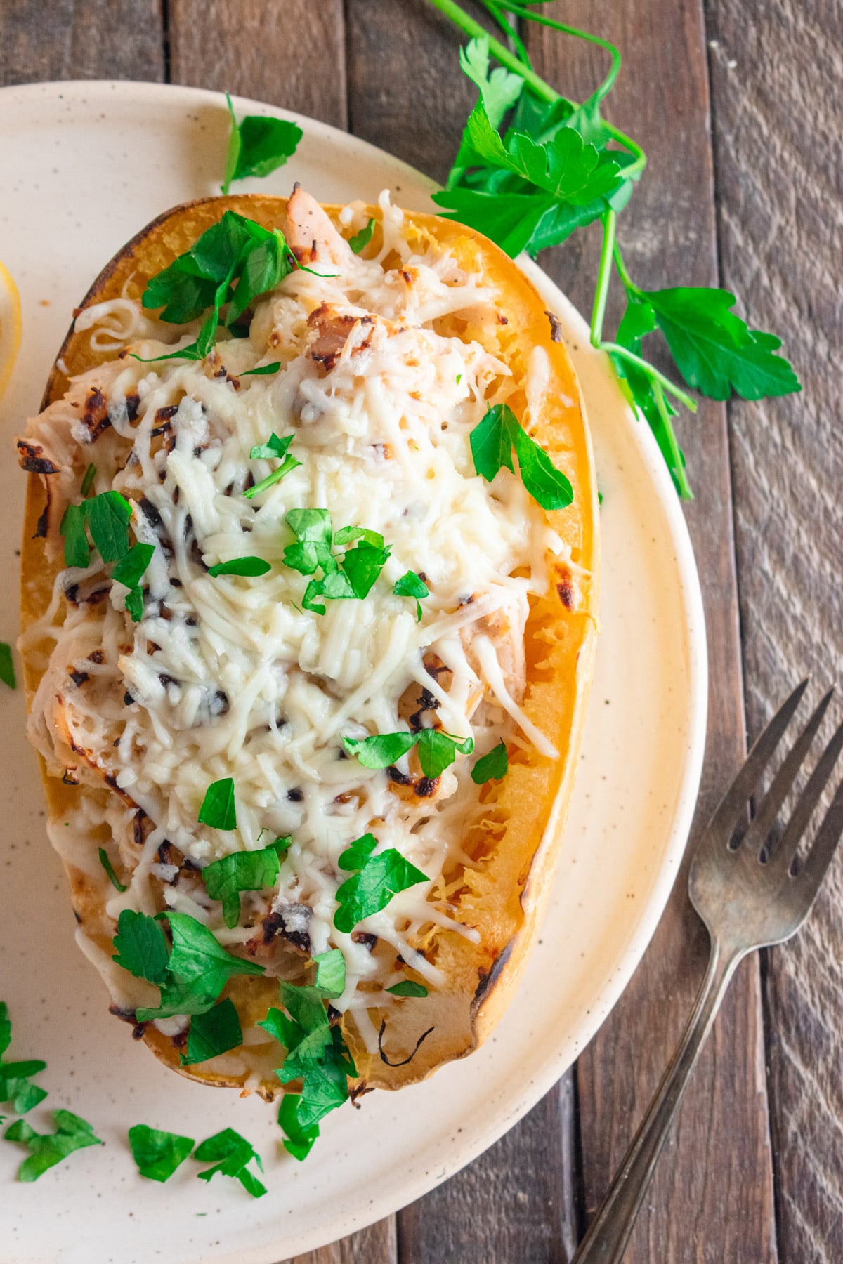 Chicken Alfredo in a spaghetti squash on a white plate on a wooden table.