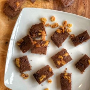 healthy flourless brownies on a white plate with walnuts on top