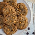 Butterscotch chocolate chip cookies on a white plate with chocolate chip morsels scattered about.