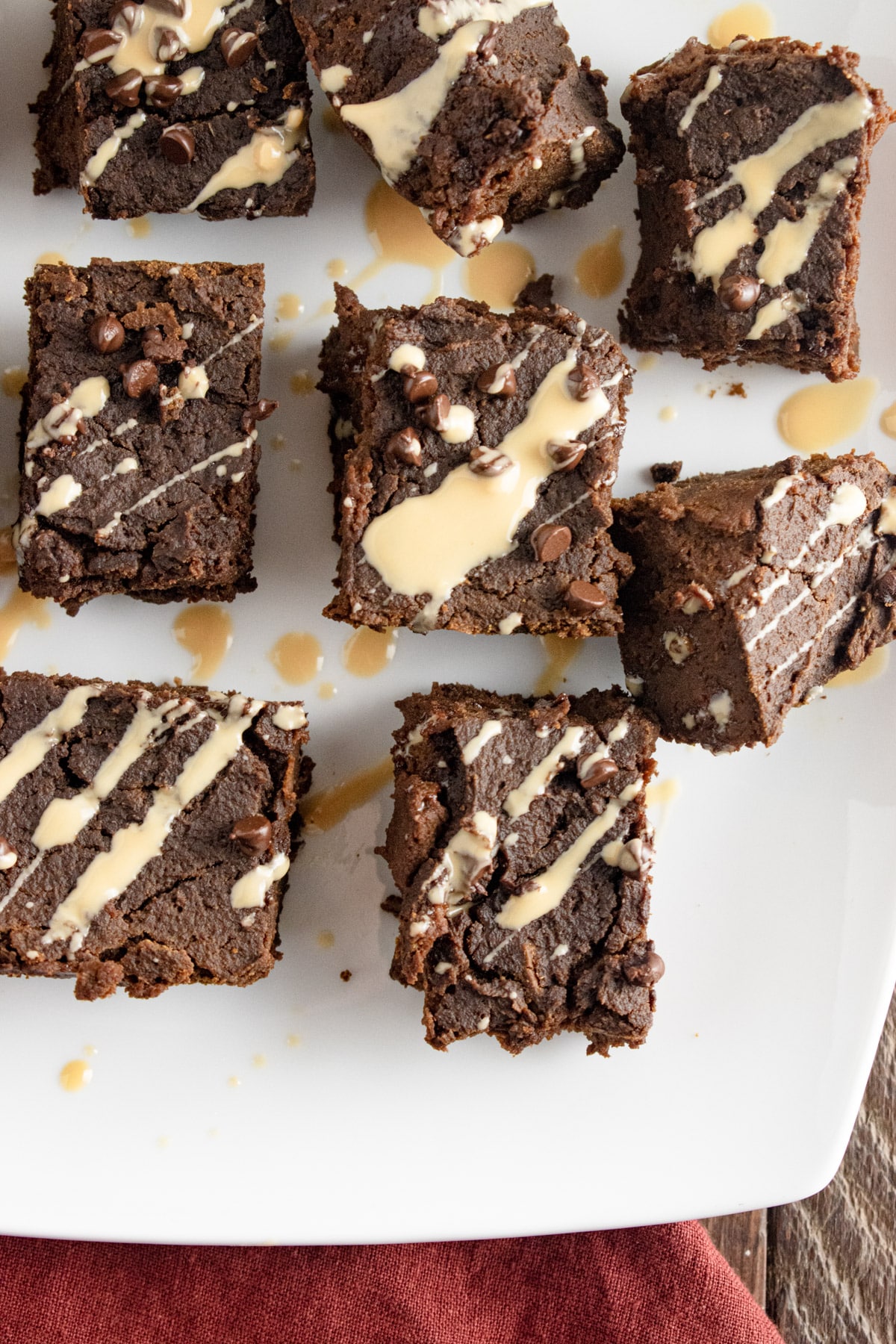 Close up of pumpkin protein brownies on a white plate with a maroon napking laid to the side.