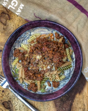 birds eye view of walnut bolognese in a colorful bowl on a wooden board