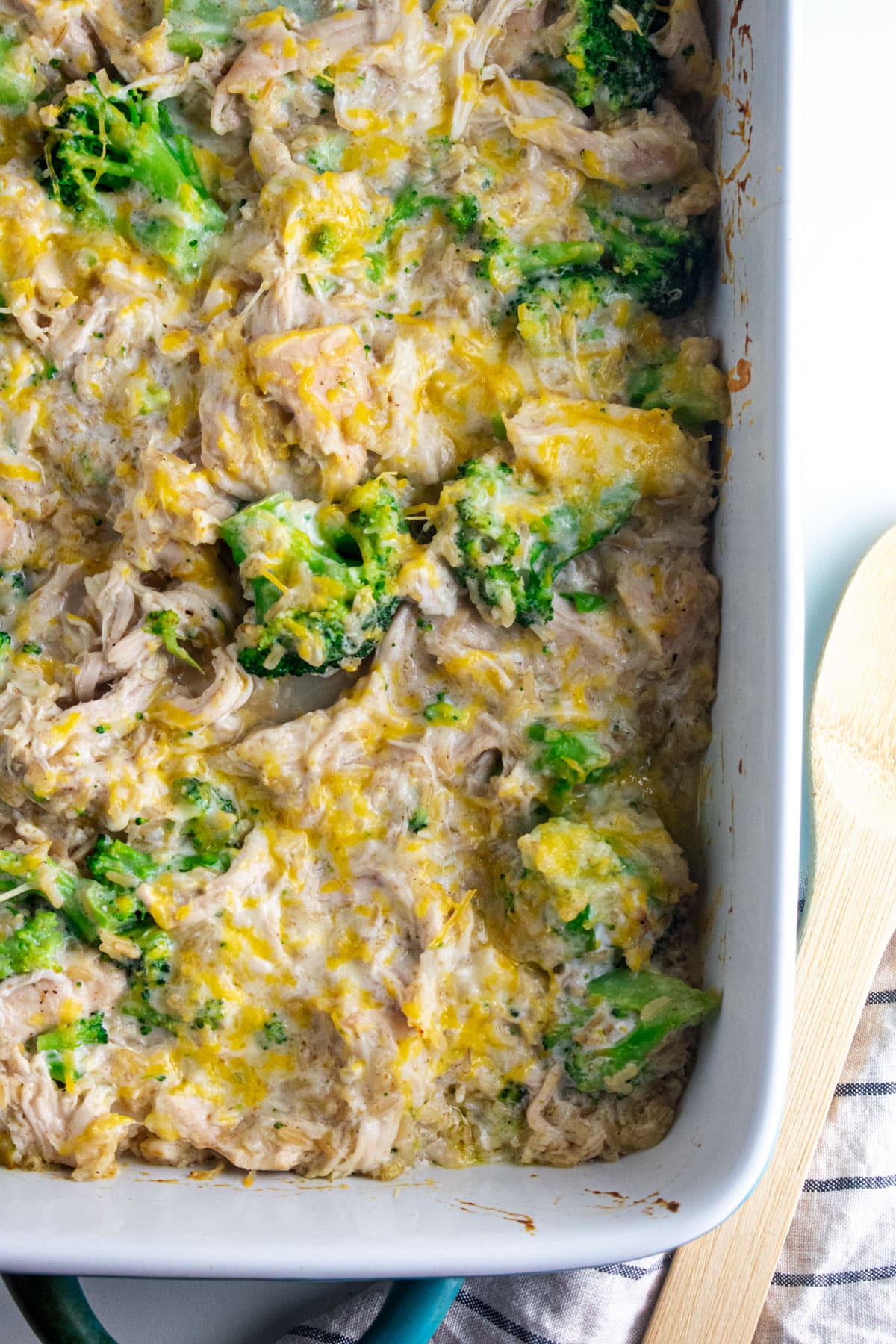 Broccoli chicken rice casserole topped with bubbly cheese in a white casserole dish.