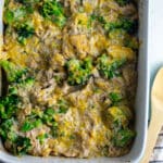 Birds eye view of cheesy chicken broccoli rice casserole in a casserole dish on a white table with a striped napkin laid to the side.