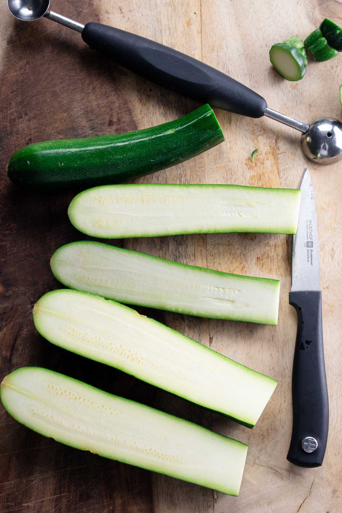 3 zucchini cut in half, lengthwise on a wooden cutting board