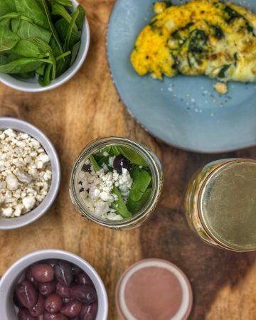 birds eye view of a breakfast jar with a greek omelette inside on a wooden cutting board