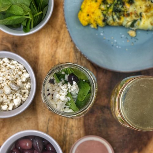 birds eye view of a breakfast jar with a greek omelette inside on a wooden cutting board