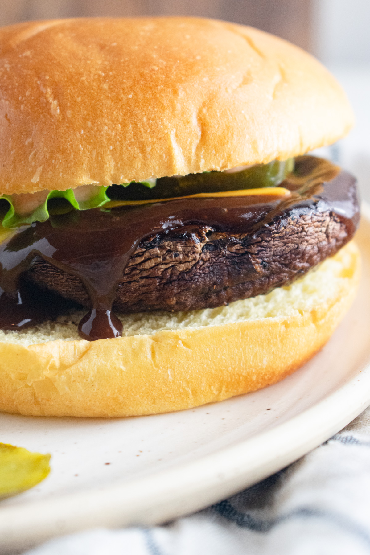 Close up of portobello mushroom burger on a bun with sauce oozing over top.