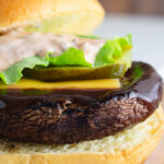 Close up of a portobello mushroom burger with steak sauce oozing over it.
