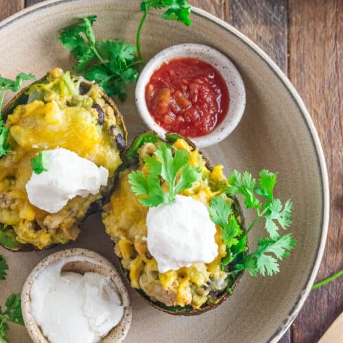 Two stuffed avocados with ground chicken, cheese, salsa, and plain greek yogurt.