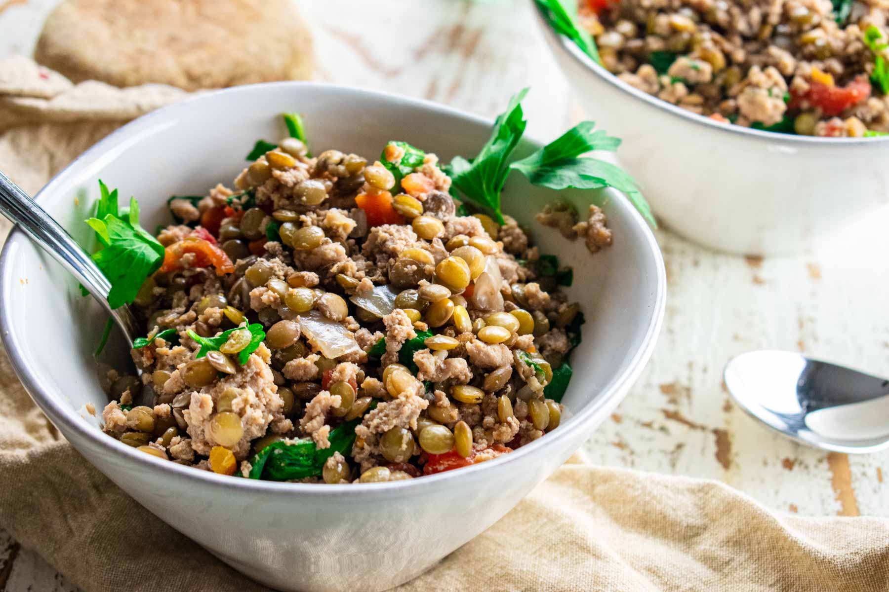 ground turkey lentil soup in a white bowl topped with fresh parsley 