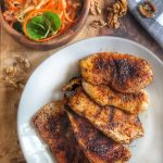 jerk chicken on a white plate with a side of spiralized veggies