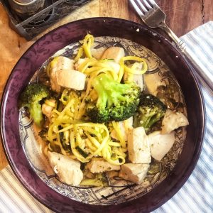 birds eye view of sweet and sour chicken with spiralized zucchini in a maroon dish