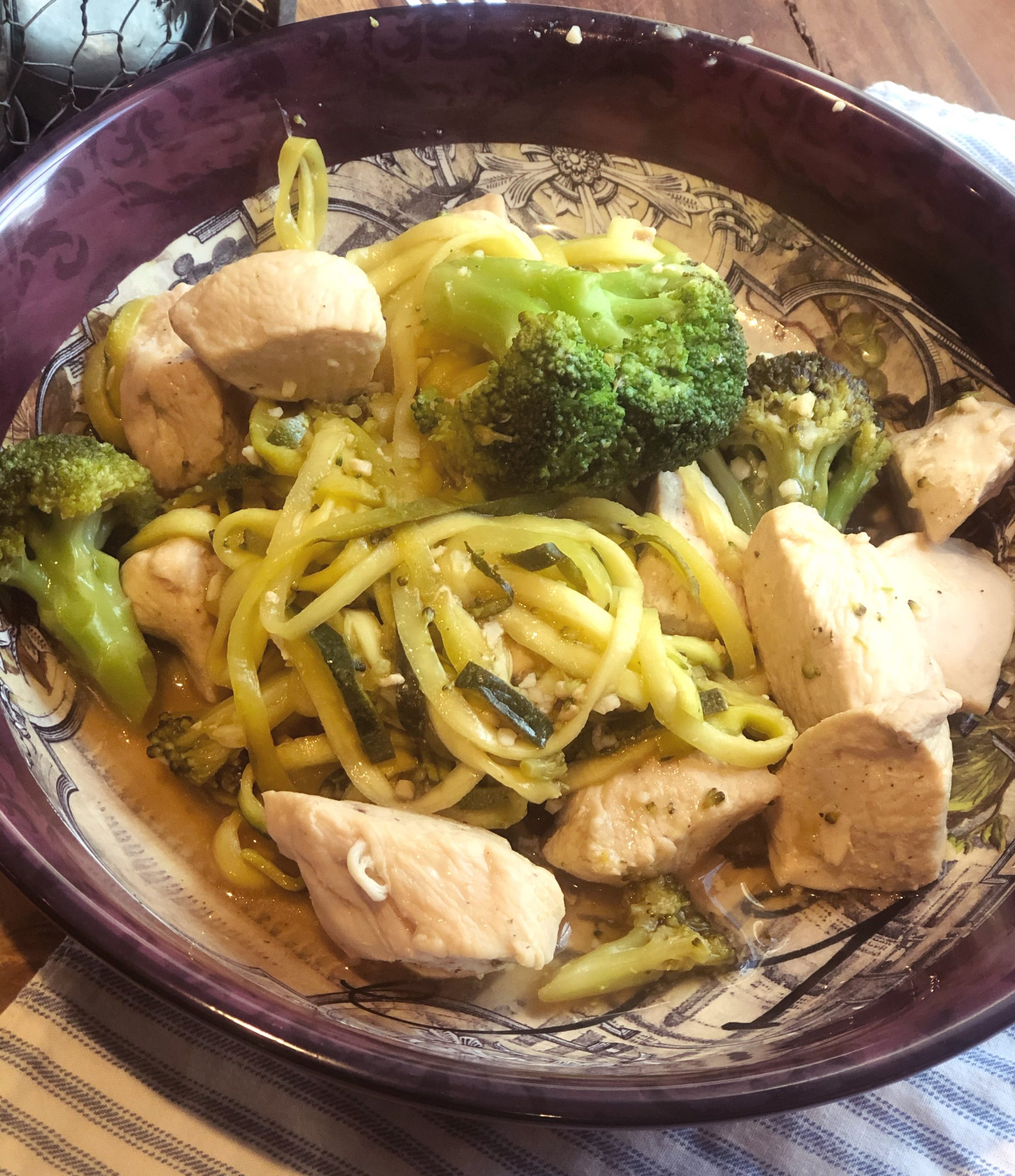 close up of healthy sweet and sour chicken with spiralized zucchini in a maroon dish