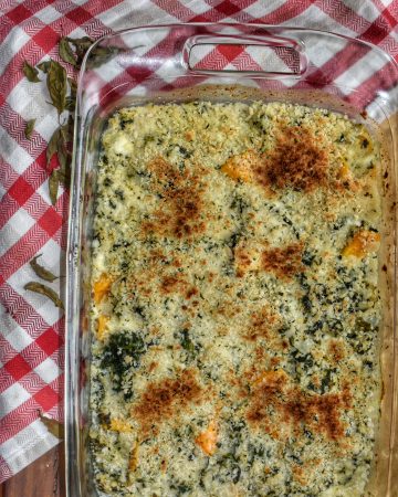 cheesy squash gratin in a glass baking dish on a red and white checkered napkin